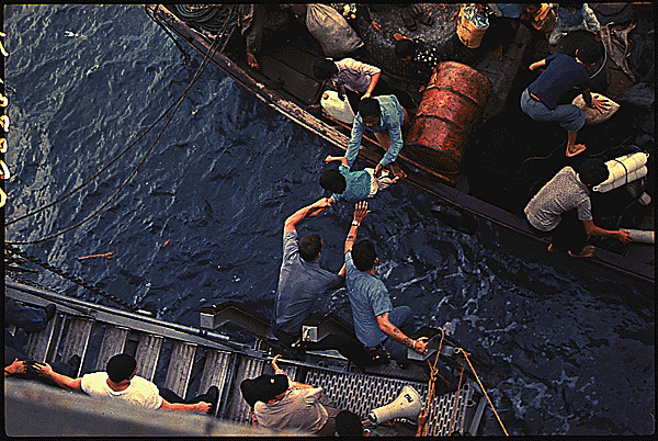 Crewmen of the Amphibious Cargo Ship USS Durham Take Vietnamese Refugees Aboard a Small Craft, 1975, via New Old Stock (Copyright Free).